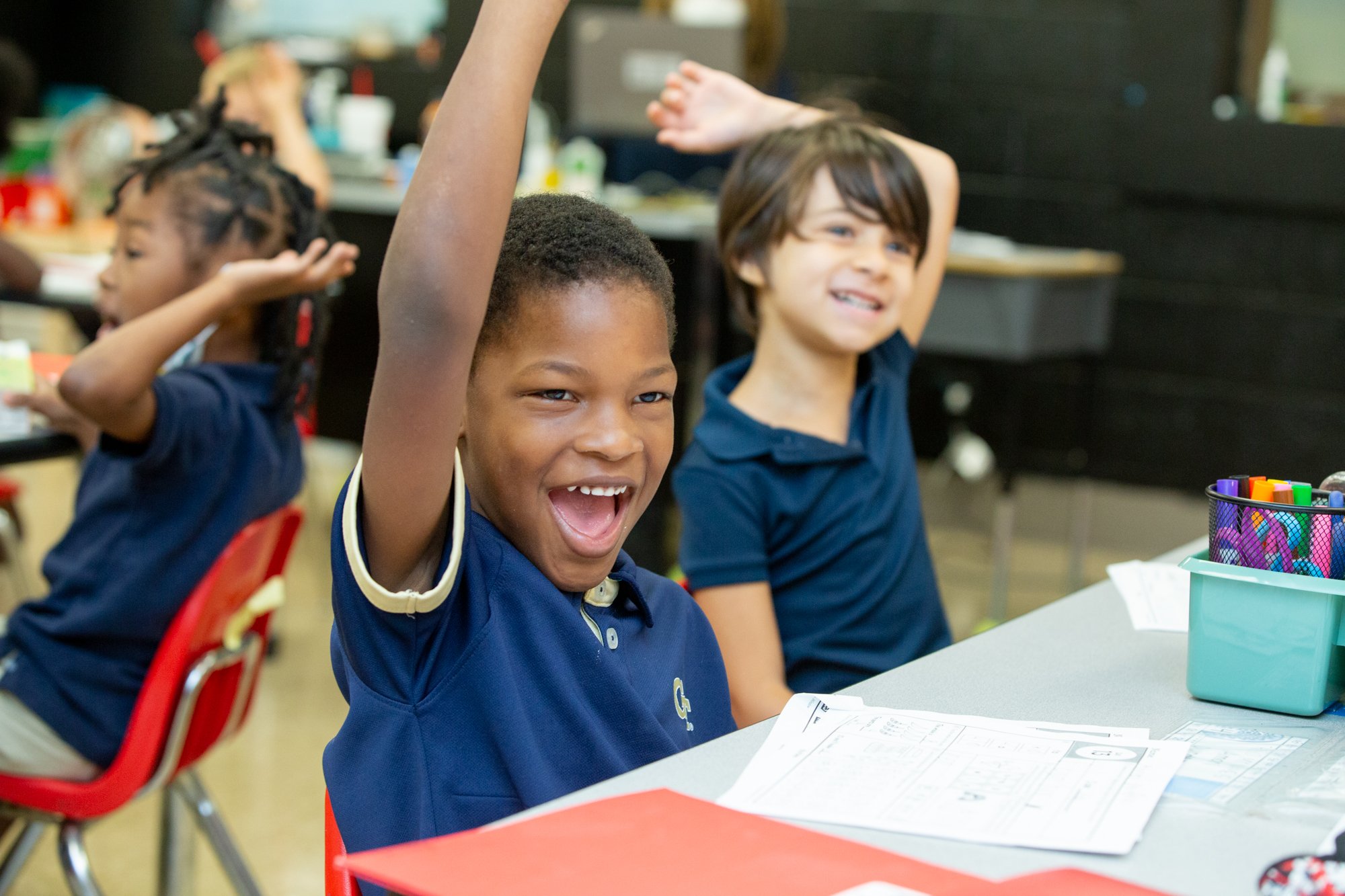 Westside students raising their hands in class