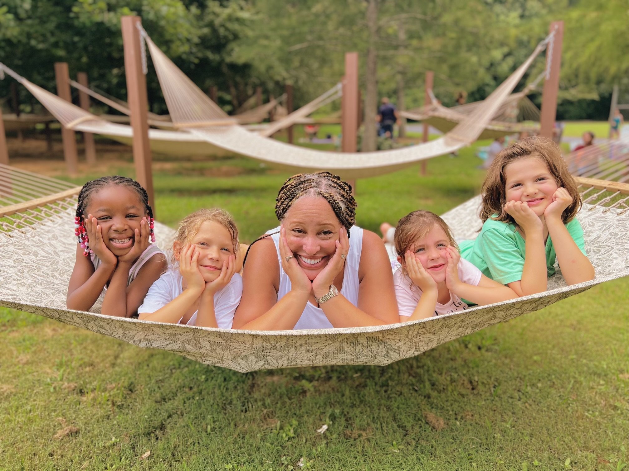 Westside students and a staff member smiling together in a hammock at a family picnic