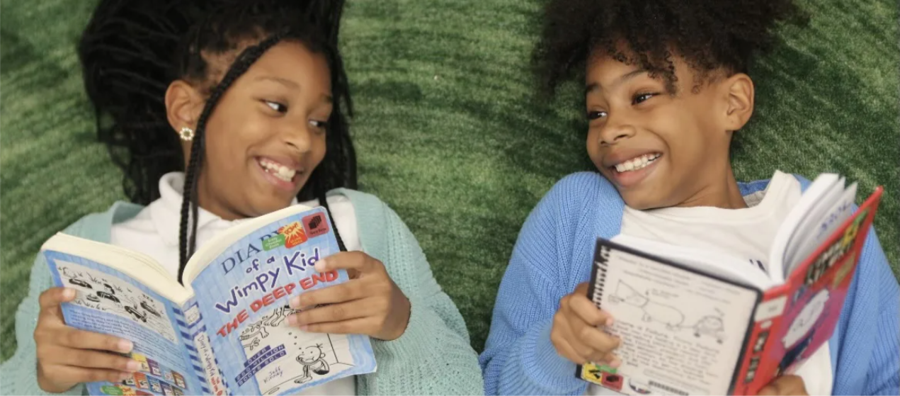 Two Westside students smiling and reading books